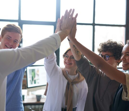 Optimiser la communication interne et externe en entreprise Équipe de professionnels célébrant une réussite lors d'une activité de team building en intérieur.