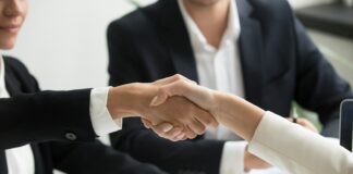 Découvrez les avantages du CESU préfinancé pour les employeurs et salariés two people shaking hands in front of a laptop